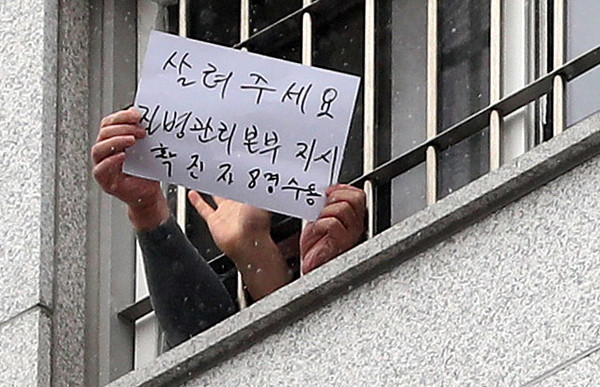 대규모 집단 감염이 발생한 서울 동부구치소에서 233명이 추가 확진돼 누적 확진자가 761명으로 집계된 29일 서울 송파구 동부구치소에서 한 수용자가 자필로 쓴 글을 취재진에게 보여주고 있다. 종이에는 '살려주세요 질병관리본부 지시 확진자 8명 수용'이라고 적혀있다. 2020.12.29 / 사진=[뉴시스]