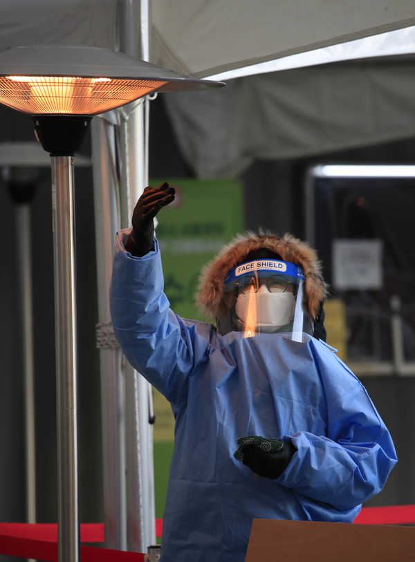 국내 신종 코로나바이러스 감염증(코로나19) 확진자 발생 1년을 하루 앞둔 19일 오후 서울 중구 서울특별시청 앞에 마련된 코로나19 임시선별검사소에서 의료진이 난로에 손을 녹이고 있다. 2021.01.19 / 사진=[뉴시스]