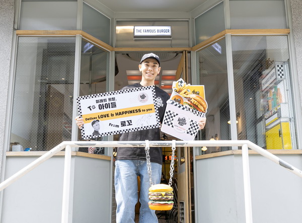 ※ 가수 로꼬가 26일(월), 더페이머스버거 신사점 앞에서 취약계층 아동 100명에게 선물할 수제 버거 도시락 모형과 응원메시지, 자필사인이 적힌 폼보드를 들고 기념촬영을 하고 있다.