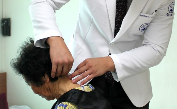 자생한방병원 의료진이 목 통증 환자에게 침치료를 실시하고 있다.