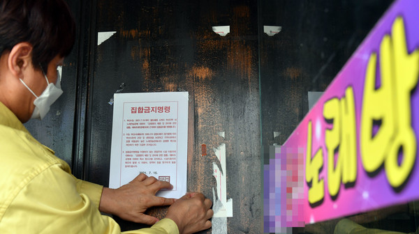 부산시는 19~25일 유흥주점·클럽 등 유흥시설을 비롯해 콜라텍과 무도장, 홀덤펍·홀덤게임장, 노래연습장 등에 대해 영업을 금지하는 집합금지 행정명령을 발령했다. 19일 오후 동래구청 공무원들이 노래연습장 출입구에 집합금지 행정명령문을 부착하고 있다. 2021.07.19 / 사진=[뉴시스]