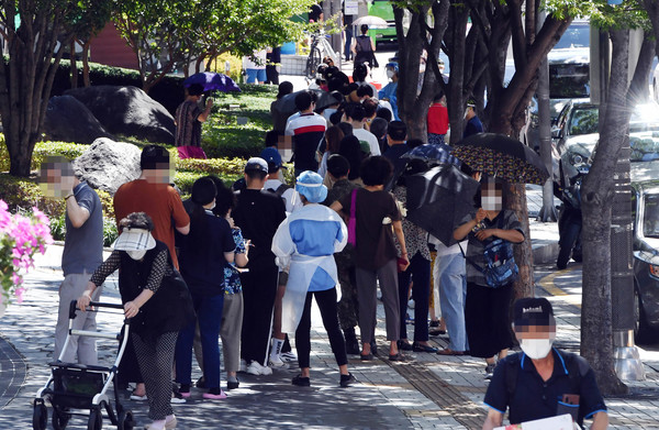 부산지역 코로나19 확산세가 심상치 않은 가운데 26일 오전 부산 남구보건소 선별진료소를 찾은 시민들이 진단검사를 받기 위해 길게 줄을 선 채 차례를 기다리고 있다. 이날 해당 보건소 주변으로 검사 대기 줄이 100m 가량 이어졌다. 2021.07.26 / 사진=[뉴시스]