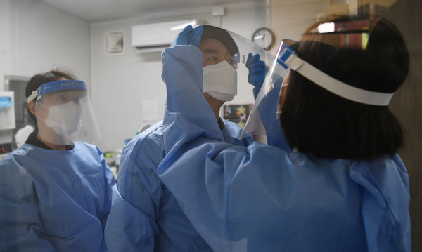 안철수 국민의당 대선 후보가 설 연휴 마지막 날인 2일 서울 중구보건소 선별진료소를 찾아 부인 김미경 교수, 딸 안설희(왼쪽) 박사와 함께 코로나19 검체 채취 봉사활동을 하기 앞서 가운과 페이스 쉴드를 착용하고 있다. 딸 안 박사는 행정 업무 등을 지원했다.2022.02.02 /  사진=[공동취재사진]