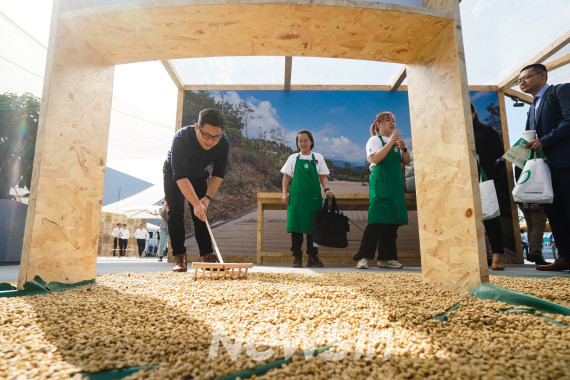 ▲19일 스타벅스 차이나 커피혁신산업단지 오픈행사 현장에서 사람들이 생두 말리기 체험을 하고 있다. (사진=신화통신)