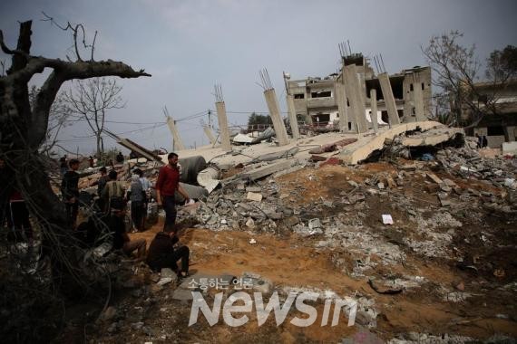 ▲29일 가자지구 남부 도시 라파에서 이스라엘 공습으로 폐허가 된 건물을 살펴보는 사람들. (사진=신화통신)