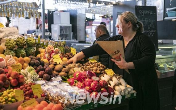 ▲지난해 12월 20일 독일 프랑크푸르트의 한 과일 가게 주인이 손님에게 과일을 팔고 있다. (사진=신화통신)
