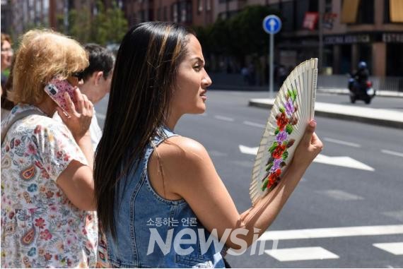 ▲지난해 7월 10일 스페인 마드리드 거리에서 한 여성이 부채질로 더위를 식히고 있다. (사진=신화통신)