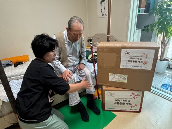 [사진설명] 자생의료재단 관계자가 독립유공자 어르신 가정을 방문해 여름 침구류 세트와 생필품을 전달하고 있다.