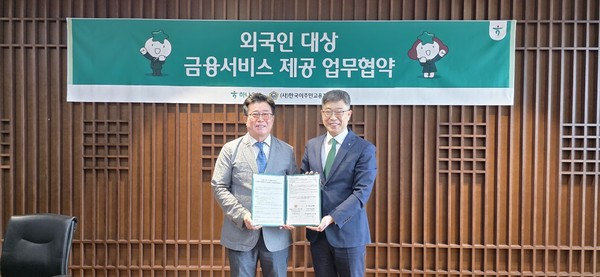하나은행 진건창 외환사업본부 본부장(오른쪽)과 (사)한국이주민고용지원중앙회 이사장 신태식(왼쪽)이 업무협약에 서명하고 기념촬영을 하고 있다.